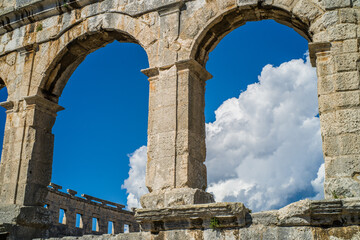 Obraz premium Roman amphitheater in the city of Pula, Croatia. Close-ups on the ancient walls of a Roman building. A beautiful sunny day with fairy-tale clouds in the background