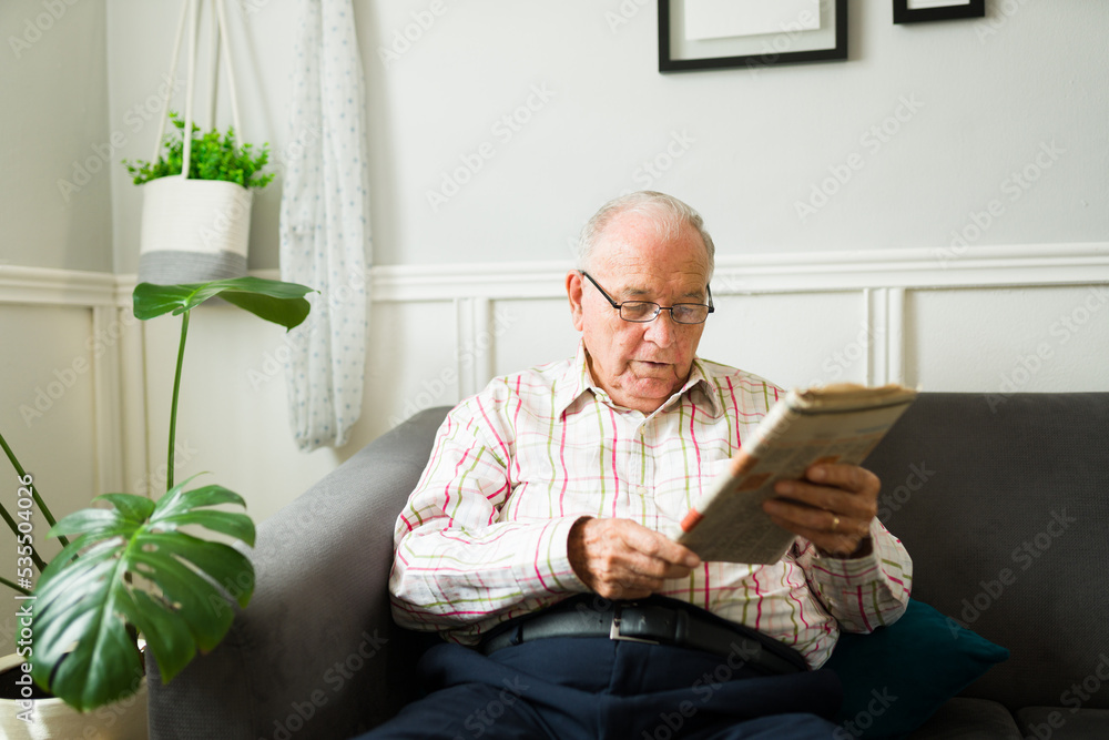 Wall mural Caucasian old senior man enjoying the newspaper in the morning at home