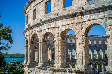 Fototapeta premium Roman amphitheater in the city of Pula, Croatia. Close-ups on the ancient walls of a Roman building. A beautiful sunny day with fairy-tale clouds in the background