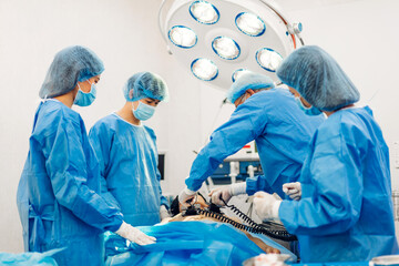 Professional anesthesiologist doctor medical team and assistant preparing patient to gynecological surgery performing operating with surgery equipment in modern hospital operation emergency room