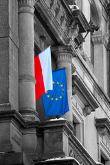 The flags of Poland and the European Union hang on the building.