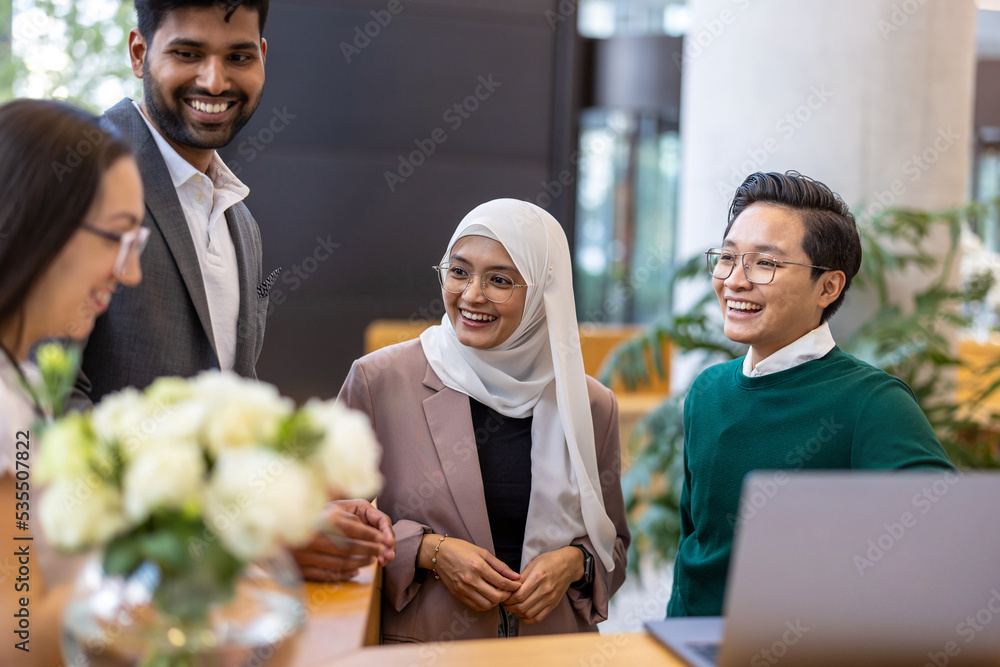 Wall mural a diverse group of business people gather around a laptop in a modern office