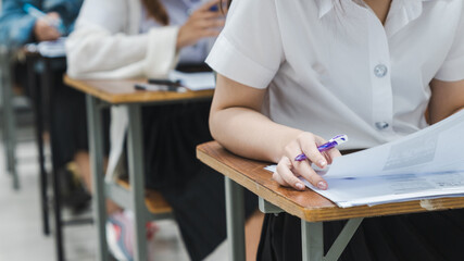 College students writing on final examination papers in the classroom concentratively