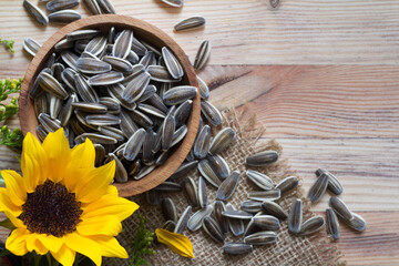 Sunflower with seeds in bowl on wooden background, concept 