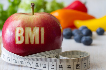 Red apple with text BMI and measuring tape on background of vegetables and fruits, diet and healthy weight concept - obrazy, fototapety, plakaty