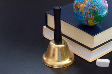 Bell, books and globe on blackboard, back to school concept