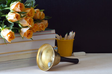 Bouquet of roses, books and bell on background of blackboard, concept back to school and Teacher Day