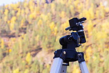 Camera tripod on natural background outdoors, selective focus with copy space. Telescope fasteners.