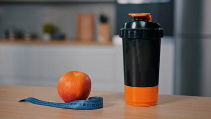 Red apple and tape measure on wooden table at home kitchen plastic bottle with water juice calcium...