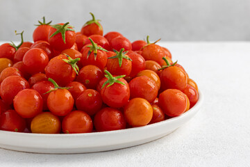 Red cherry tomatoes in a white dish on a light, minimalism
