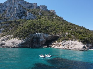 Aerial view of the famous Cala Sisine in Orosei Gulf, East Sardinia, Italy. Drone and birds eye of clear and crystalline water over the top of Punta Salinas with yacht in Sardinia (Sardegna).