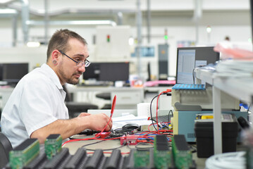 engineering in microelectronics: workers in the production and assembly of electronic high tech components in a modern factory