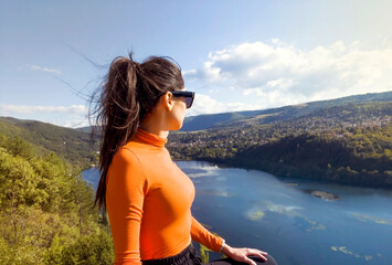 Traveler woman standing  high above a blue lake with stunning panoramic view .Traveling in the nature in Bulgaria . Pancharevo Lake