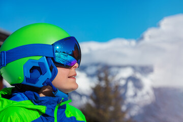 Portrait of a boy smile in ski helmet and mask over mountain