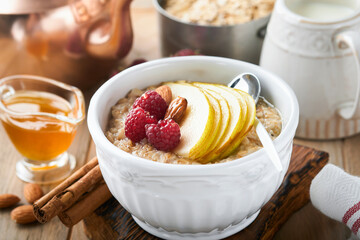Oatmeal. Bowl of oatmeal porridge with raspberry, pear and honey on old wooden table background. Hot and healthy food for Breakfast, top view, flat lay