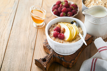 Oatmeal. Bowl of oatmeal porridge with raspberry, pear and honey on old wooden table background. Hot and healthy food for Breakfast, top view, flat lay