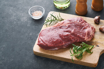 Steaks. Fresh New York Steaks raw with spices rosemary and pepper on black marble board on gray...