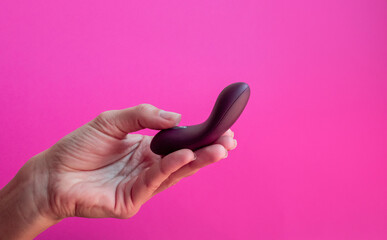 Sex toy for women, female hands holding a masturbator on the pink background.