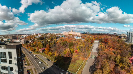 Obraz premium Aerial autumn Kharkiv Botanical Garden near streets with lively cars traffic. Tourist attraction in Shevchenko City Garden with modern buildings and scenic sky in Kharkiv, Ukraine