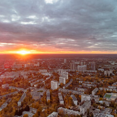 Aerial vivid autumn city sunset view with sun shine in gray clouds. Residential district buildings...