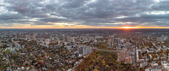 Aerial vivid autumn city park sunset panorama view with epic clouds. Residential district buildings and cars driving in evening light. Kharkiv, Ukraine