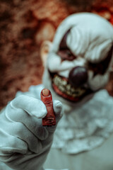 evil clown showing a bloody amputated finger
