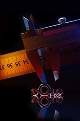 metal, chrome-plated nuts of different sizes and a caliper measuring the nut. Black background