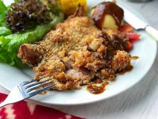 Close up chicken Chopin the white plate on the white table background.Mashed potatoes, fork and knife at the side and vegetables.Crispy.ready to eat.fry with air fryer or deep fry.
