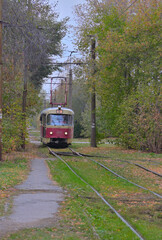 Fototapeta na wymiar An old tram car rides on rails on an autumn day