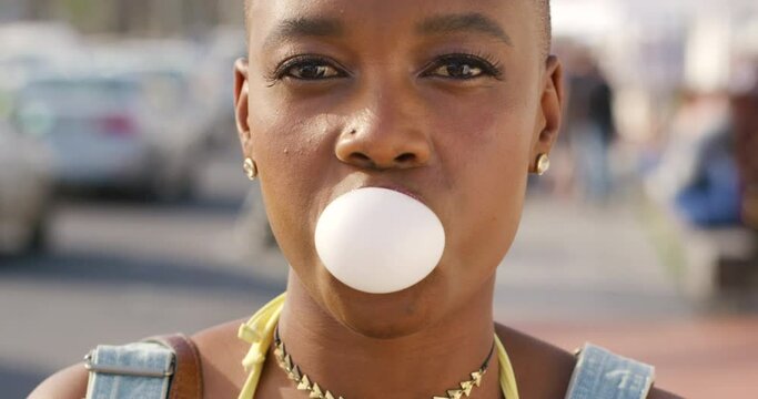 Gum, bubble and black woman with a happy smile and crazy, funny and comic energy outdoors. Portrait of a female from Kenya with happiness and comedy mindset blowing bubbles with blur background