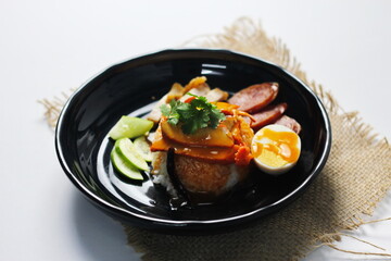 rice with roasted pork on top served with cucumber, boiled egg, crispy pork and bbq sauce that are sold in many places in Thailand.Barbecued red pork in sauce with rice is a popular food in Thailand.