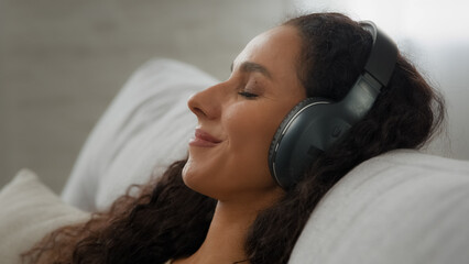Closeup happy calm inspired Hispanic Latino Caucasian 30s smiling woman lying on couch sofa with...