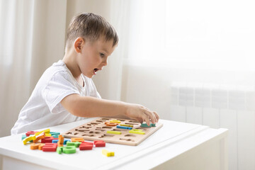 Male kid playing with wooden eco friendly alphabet letters board on table top view intellectual game