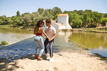 beautiful woman and handsome man latinos dancing bachata are dancing by the river in the forest....