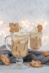 Pumpkin spice latte in a glass mug with caramel and cinnamon cookies with Autumn decoration