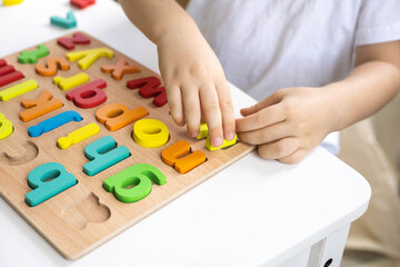Male kid playing with wooden eco friendly alphabet letters board on table top view intellectual game