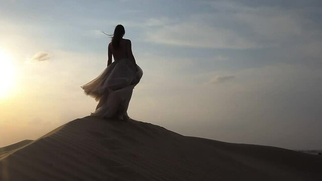 A girl in a shiny dress dances barefoot in the sand