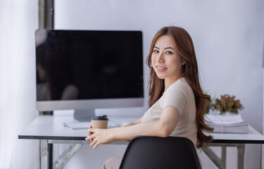 Fototapeta na wymiar Portrait of Young Asian businesswoman is happy to work at the modern office using a laptop computer, freelance business employee online marketing e-commerce telemarketing concept.