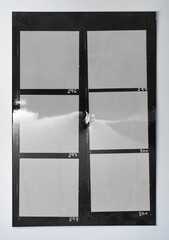 photo of torn black and white handcopy contactsheet with blank film frames and deep cutting hole. shiny photo paper.