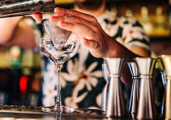 man hand bartender pouring cocktail in glass on the bar counter