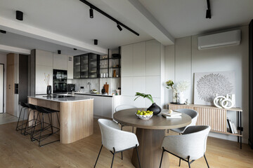 Contemporary design of dining room interior with round table, gray chairs, wooden floor,...