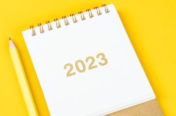 The 2023 Desk calender with wooden pencil on yellow background.