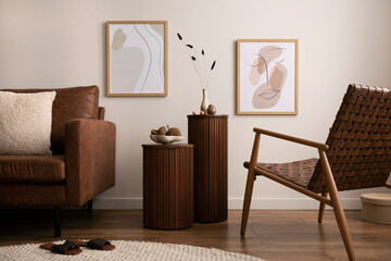 Minimalist composition of elegant and warm space with brown sofa, wooden side tables, rattan armchair, mock up poster frames, round rug, decoration and elegant personal accessories. Home decor. 