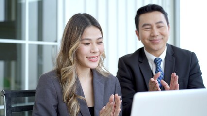 Asian businessman and businesswoman talking together in an office.