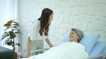 Obraz premium Senior elder Asian female patient resting on the medical bed in hospital and talking to her daughter.