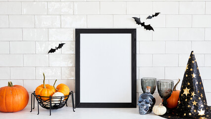 Happy Halloween holiday concept. Picture frame mockup with witch hat, pumpkins, skull, wine glasses, bats on table in nordic home interior
