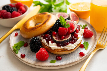 Toasted baggels with red fruit jam, blackberries, raspberries and cheese, figs based on fresh cheese. vegan breakfast.