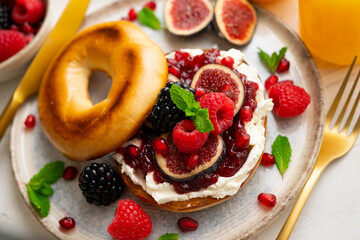 Toasted baggels with red fruit jam, blackberries, raspberries and cheese, figs based on fresh cheese. vegan breakfast.