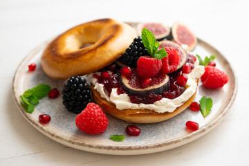 Toasted baggels with red fruit jam, blackberries, raspberries and cheese, figs based on fresh cheese. vegan breakfast.