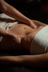 Girl enjoying therapeutic massage with oil in spa with dark lighting, closeup